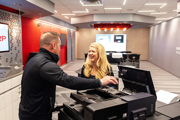 Two people looking at a copier and printer
