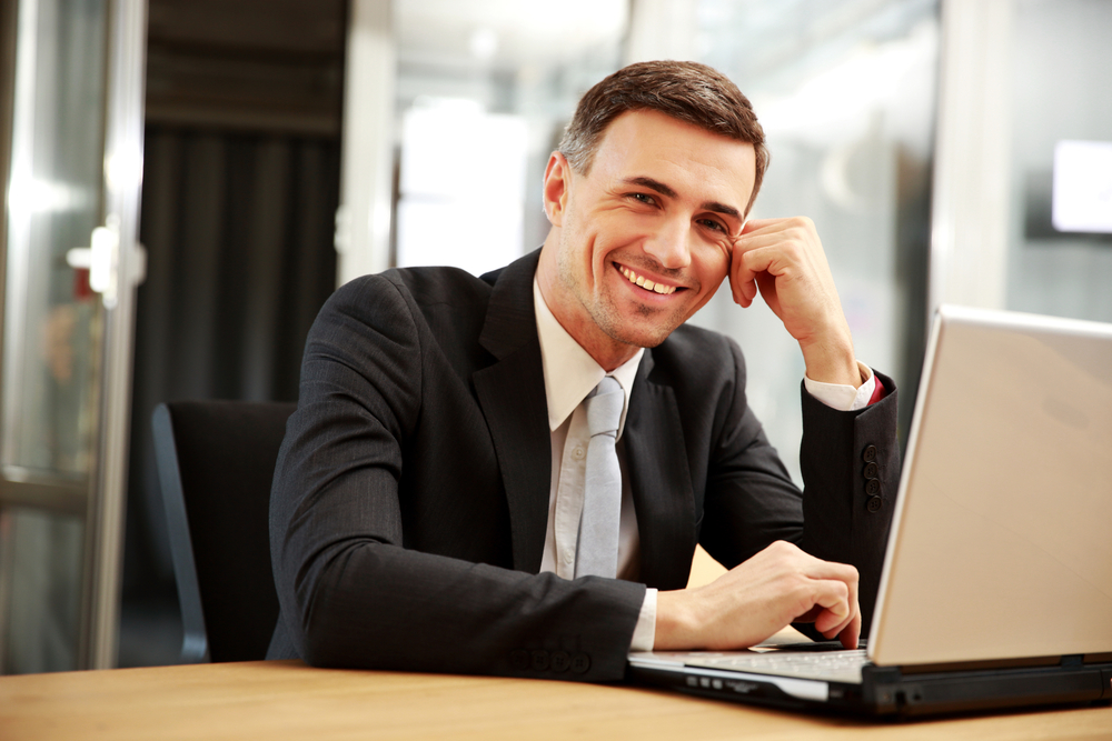 man in suit sitting at a table on laptop