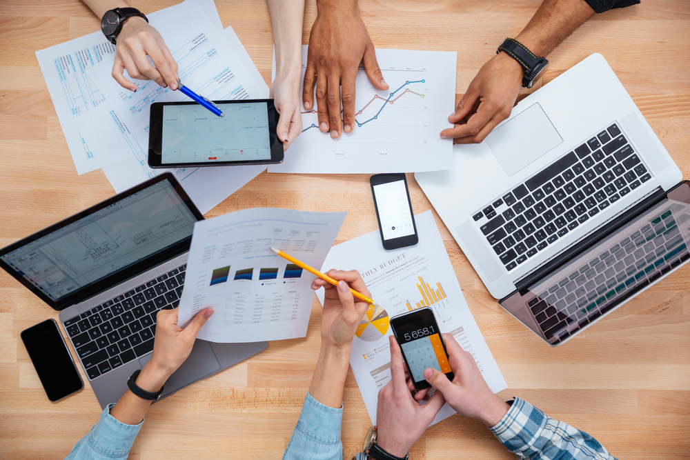 Employees using laptops, tablets, and phones for work