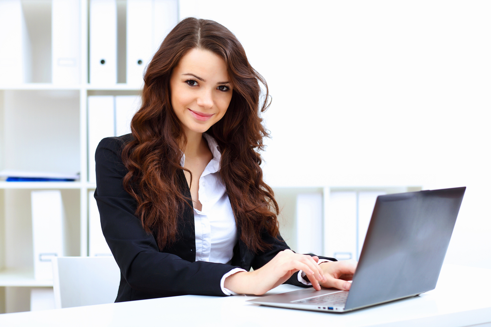 woman in blazer sitting at desk on a laptop